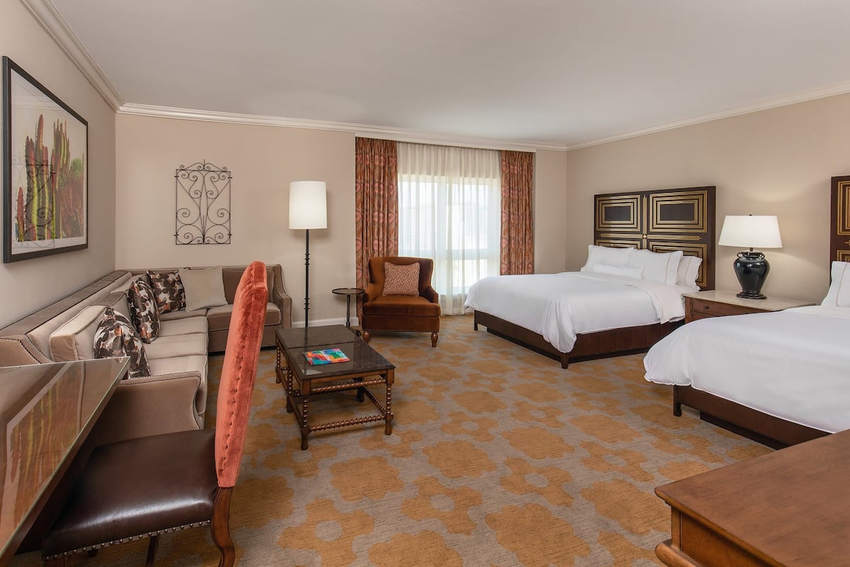 Een hotelkamer met twee bedden, een bank, een stoel, een tafel en een lamp.