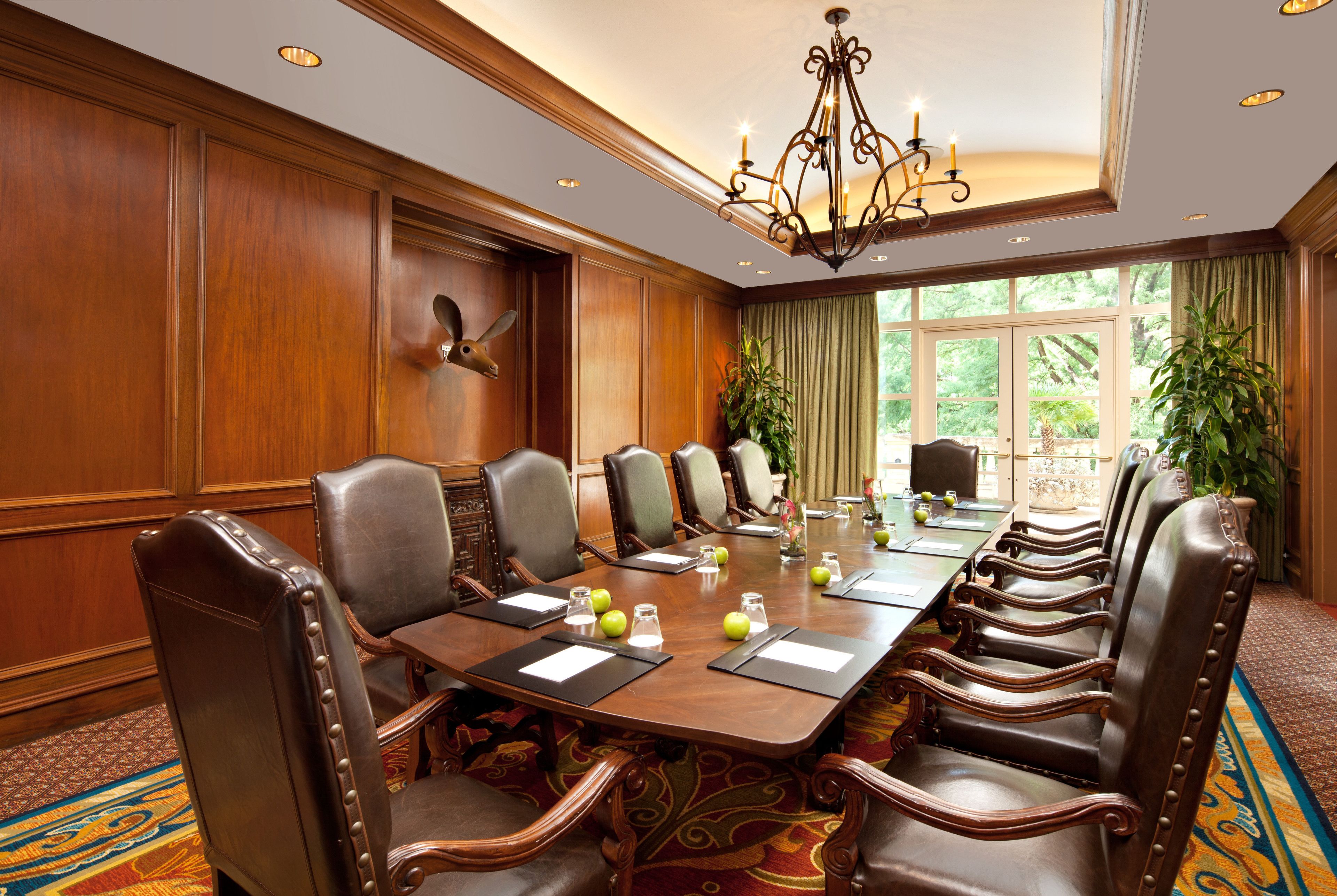 A conference room with a long table, leather chairs, and a chandelier.
