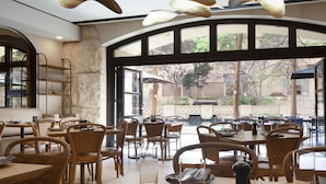 A restaurant interior with multiple dining tables, chairs, and hanging pendant lights.