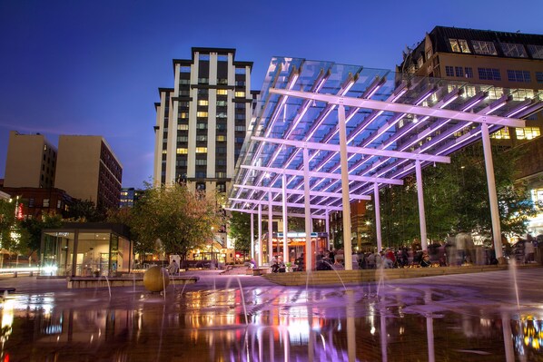 Experience the vibrant atmosphere of this urban plaza, surrounded by contemporary buildings and a stunning water feature.