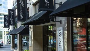 Fachada de hotel con varias toldillas negras, un llamativo letrero 'SWINE' y una entrada de vidrio.