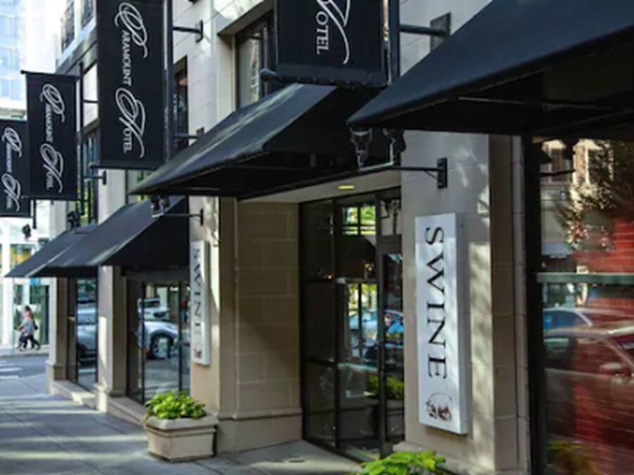 A hotel facade with multiple black awnings, a prominent 'SWINE' sign, and a glass entrance.