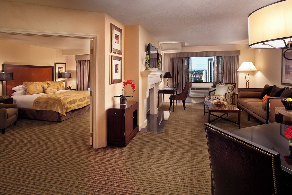 Quarto de hotel com cama, escrivaninha, sofá e mesa de jantar.
