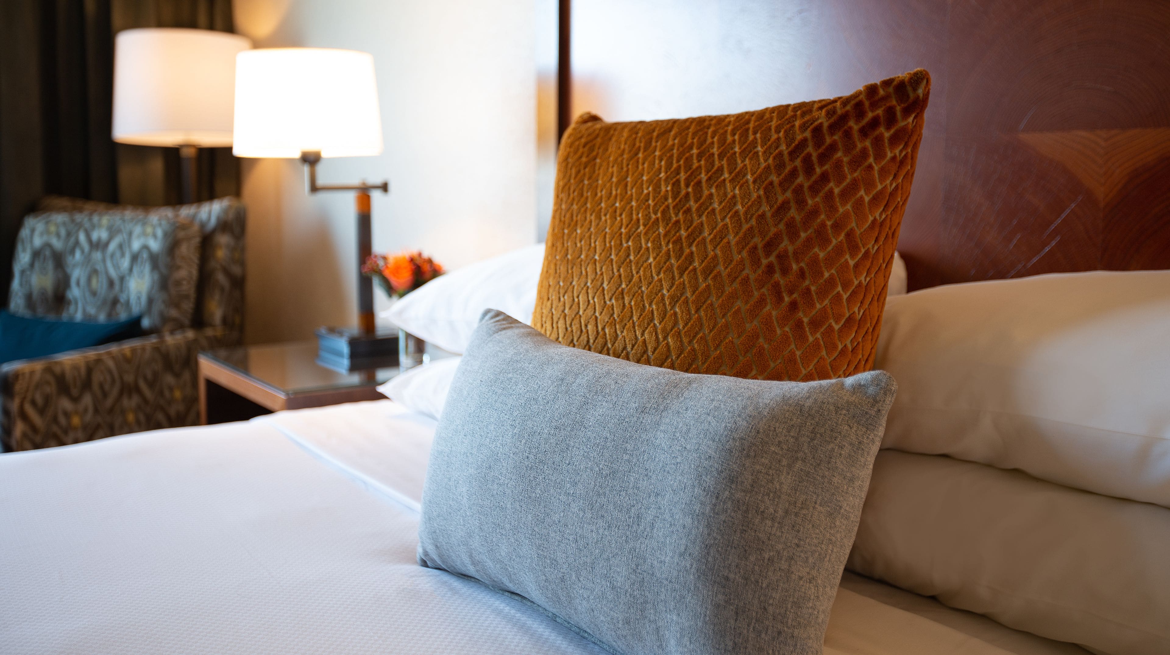 A neatly made bed with a grey pillow and a textured brown pillow.