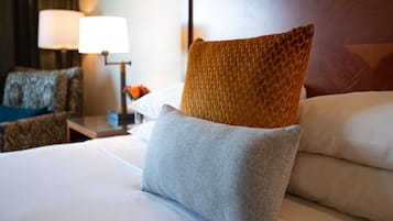 Una cama bien tendida con un almohadón gris y un almohadón marrón texturizado.