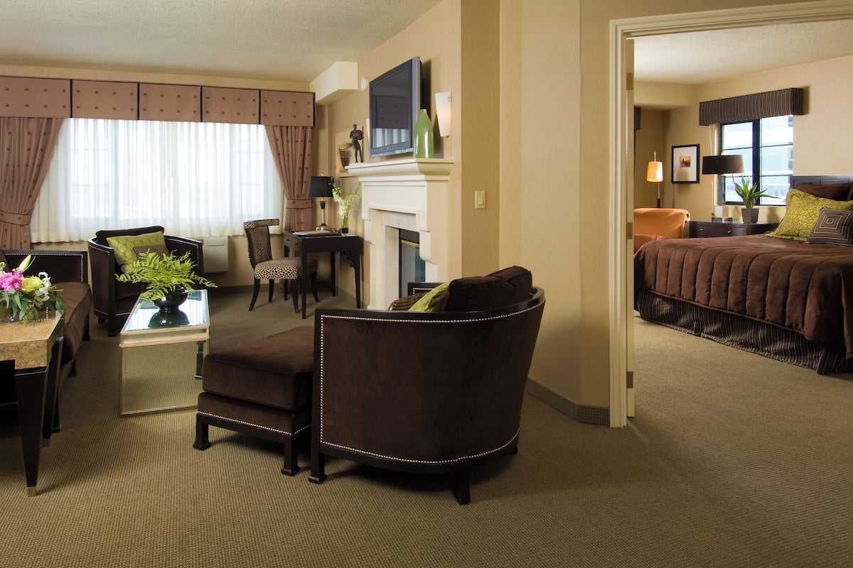 Quarto de hotel com área de estar, mesa de jantar, sofá, lareira e cama.