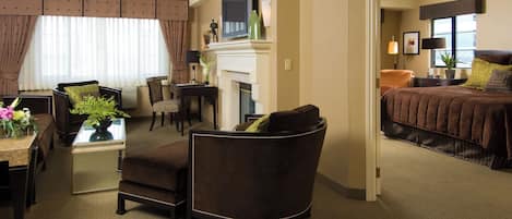 Una habitación de hotel con sala de estar, una mesa de comedor, sofá, chimenea y cama.