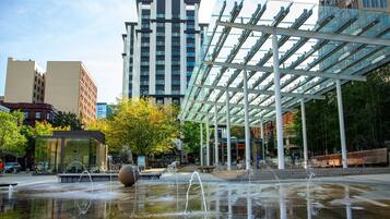 A modern urban plaza with a water feature and a glass pavilion.