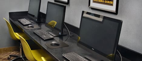 Una fila de estaciones de trabajo con monitores, teclados y sillas.