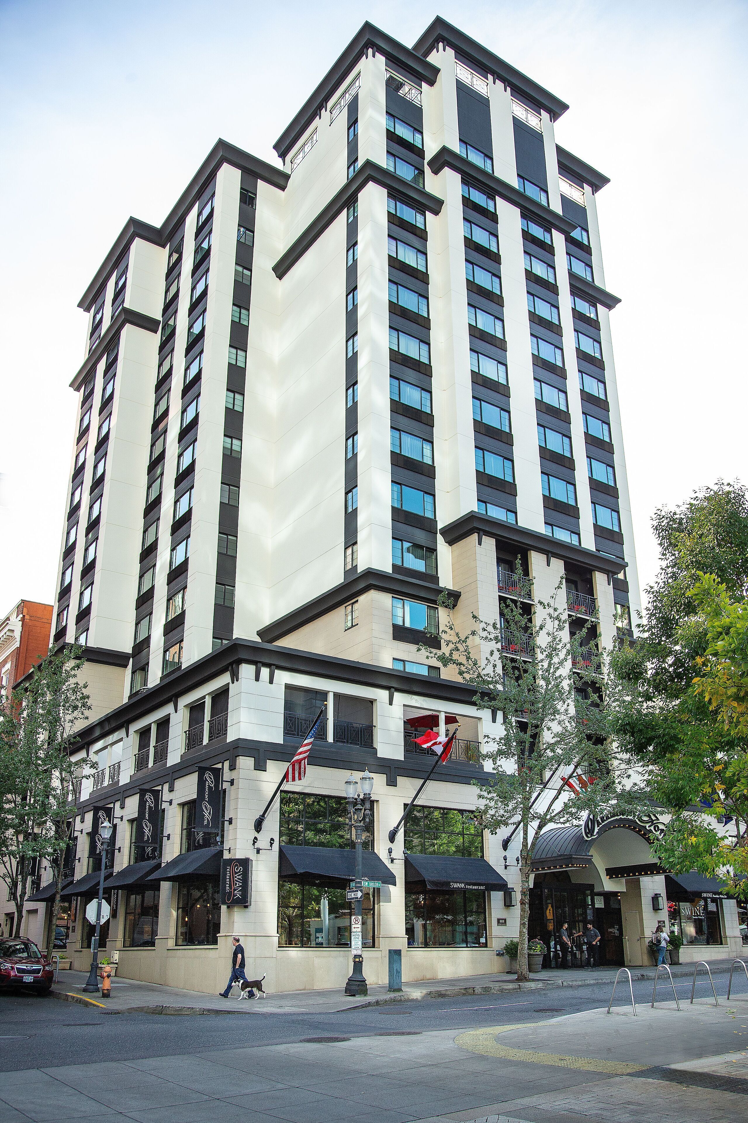 Um hotel de vários andares com design arquitetônico moderno, destacando uma entrada imponente com toldos e uma bandeira americana visível.