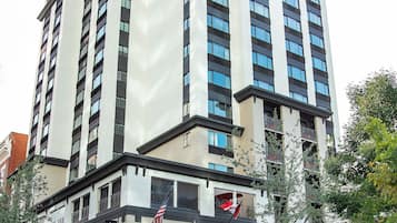 Um hotel de vários andares com design arquitetônico moderno, destacando uma entrada imponente com toldos e uma bandeira americana visível.