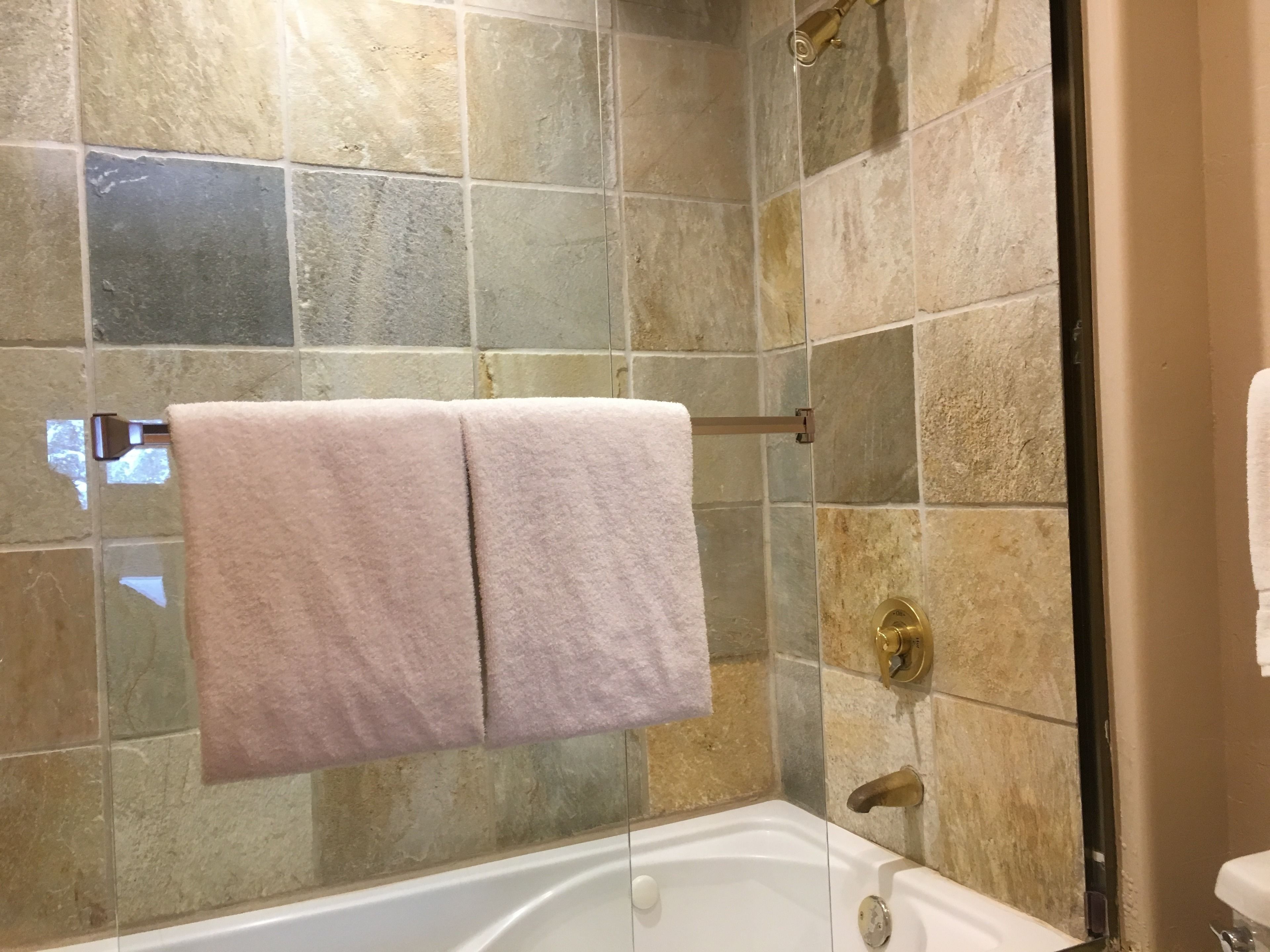Un bany amb banyera, una cabina de dutxa de vidre i un suport de tovalloles amb dues tovalloles.