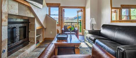 A living room with a stone fireplace, leather sofa, and a large TV mounted on the wall.