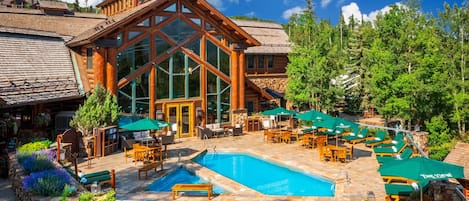 A lodge with a large glass facade, outdoor pool, and patio seating.