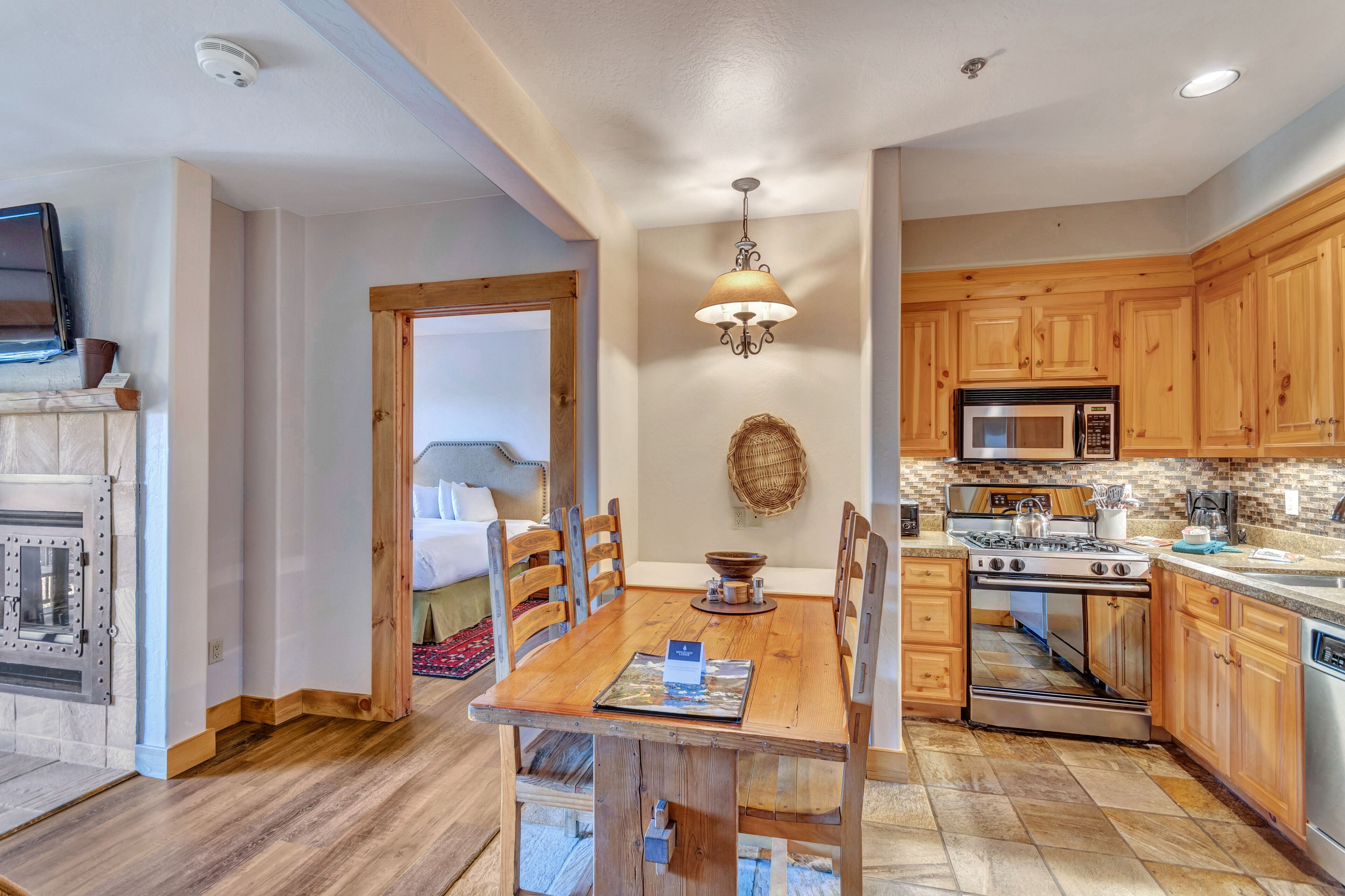 A kitchen with wooden cabinets, a stove, microwave, and a dining table with chairs.