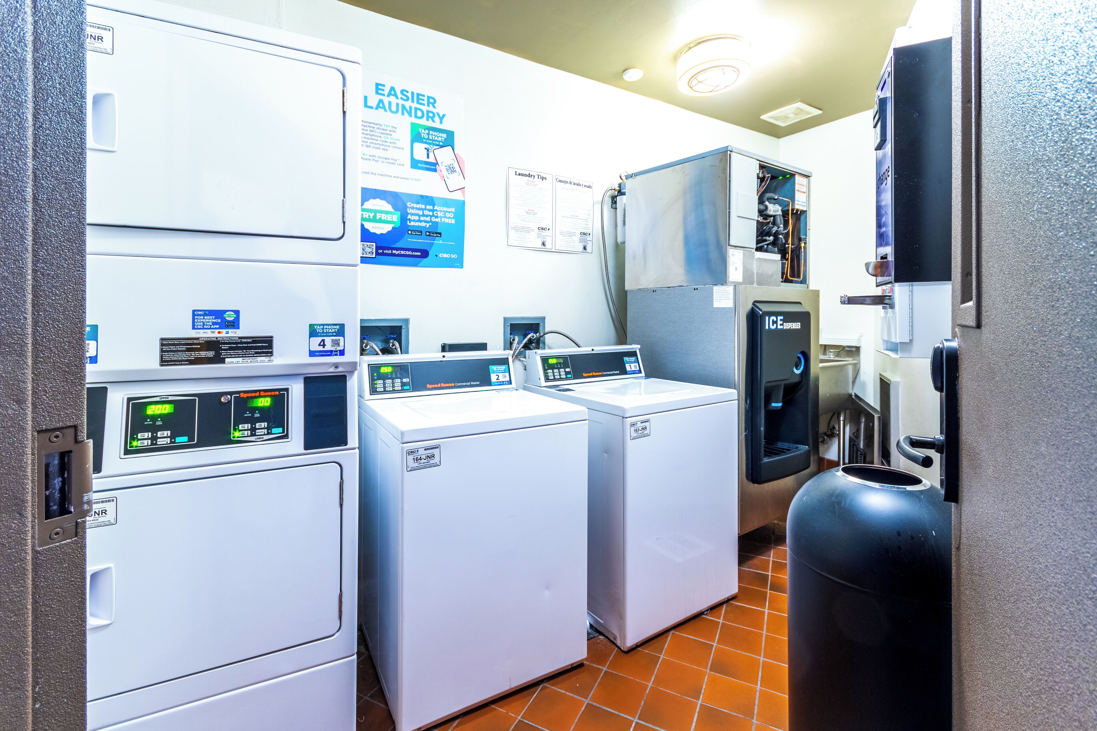 A laundry room with two front-loading washers and a top-loading dryer.