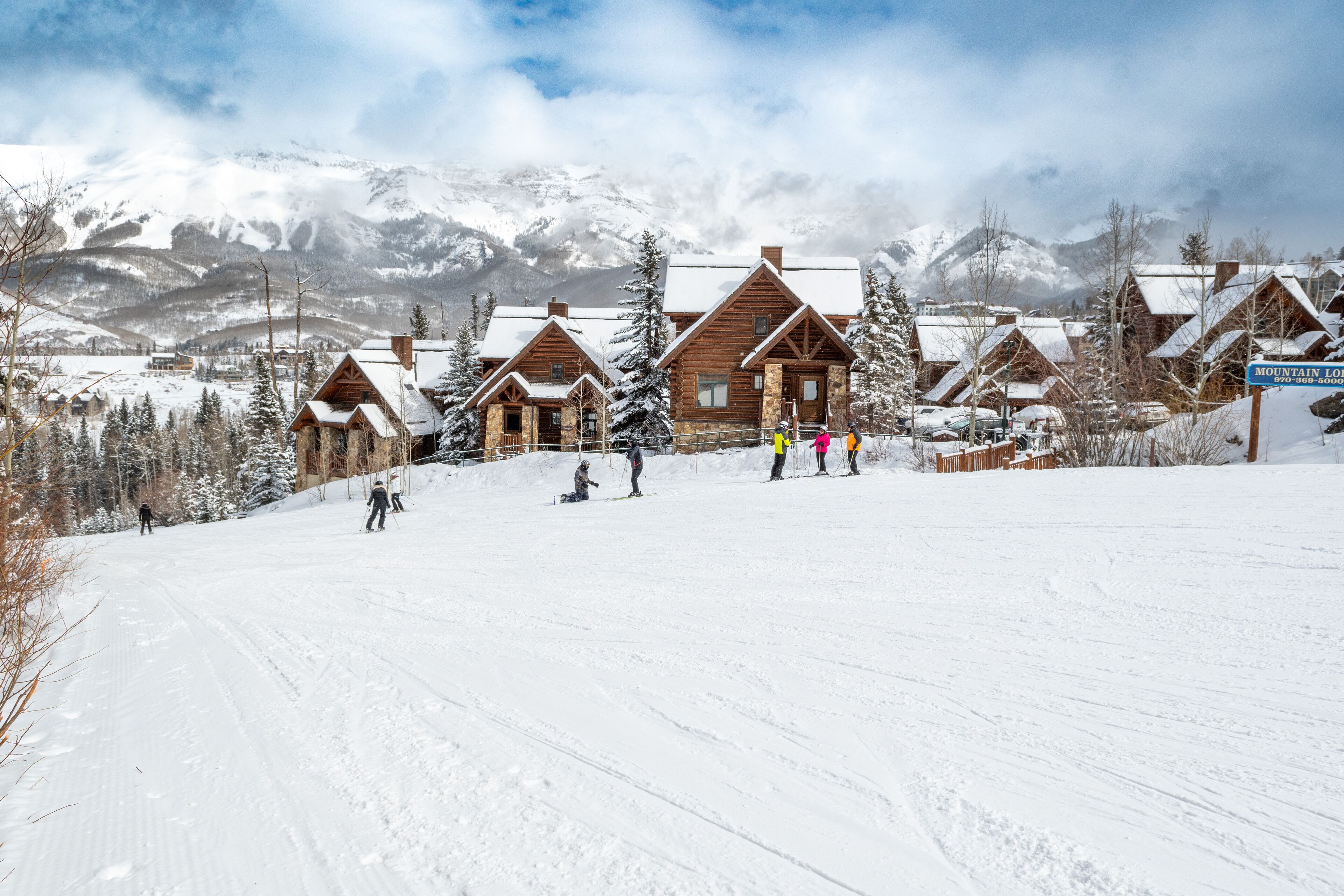 Ein schneebedecktes Skigebiet mit Holzhütten und Bergblick.