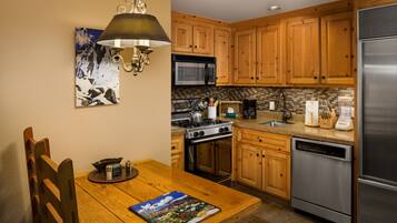 A kitchen with wooden cabinets, a stainless steel refrigerator, a microwave, a stove, and a dishwasher.
