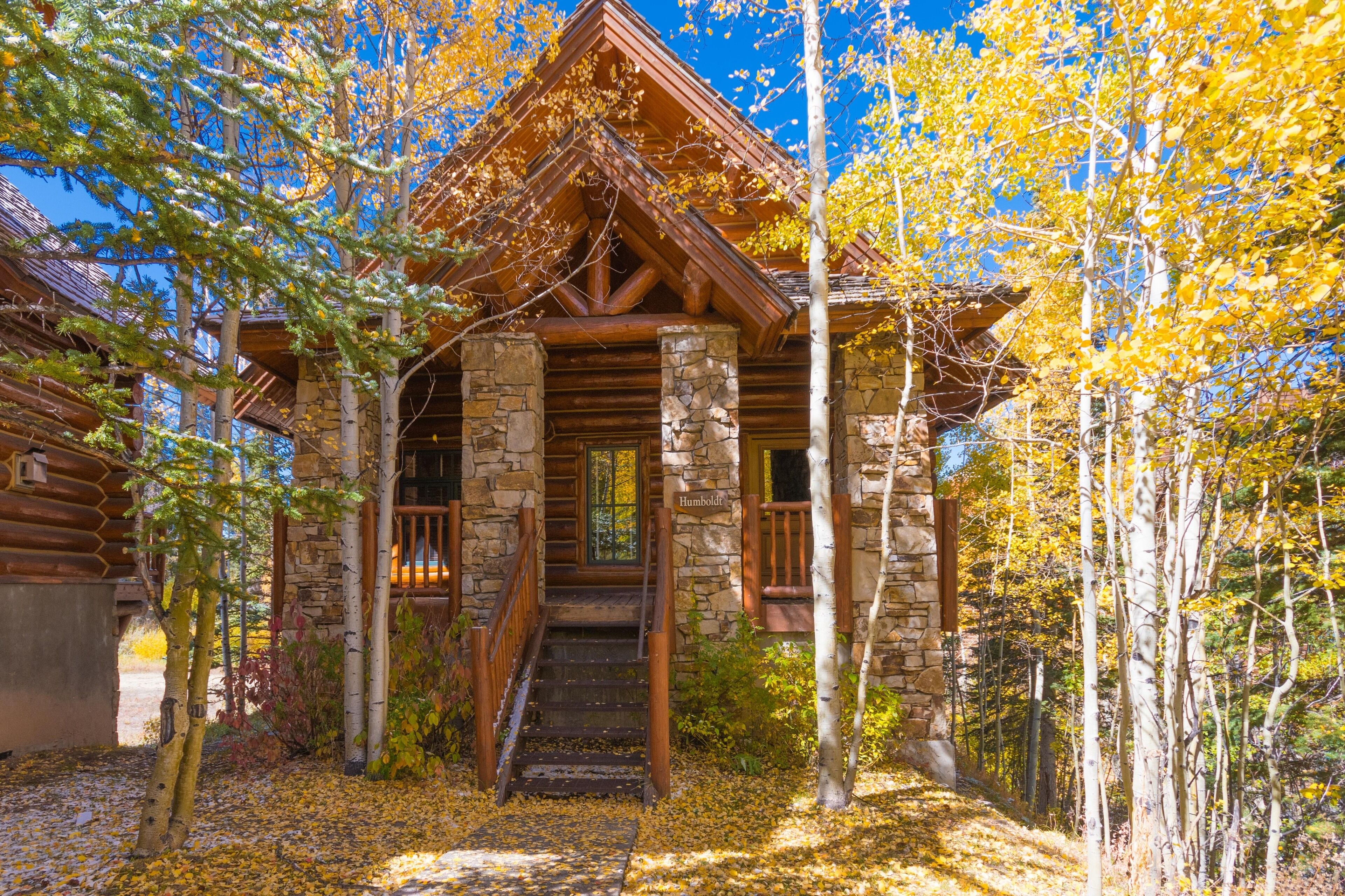 A log cabin with a stone foundation, wooden beams, and a wooden staircase leading to a door labeled "Humboldt."