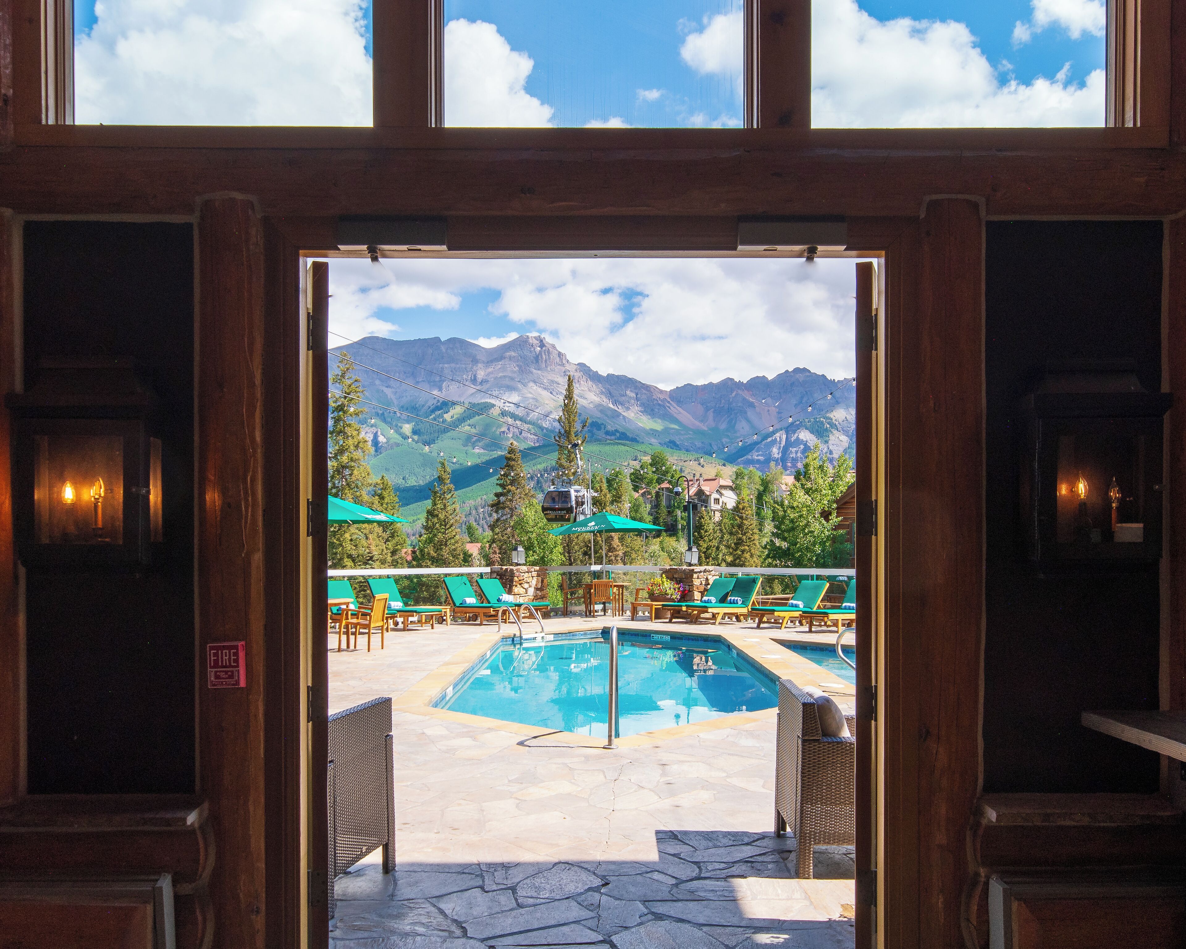 A pool area with lounge chairs and a view of mountains.