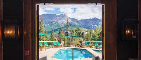 A pool area with lounge chairs and a view of mountains.
