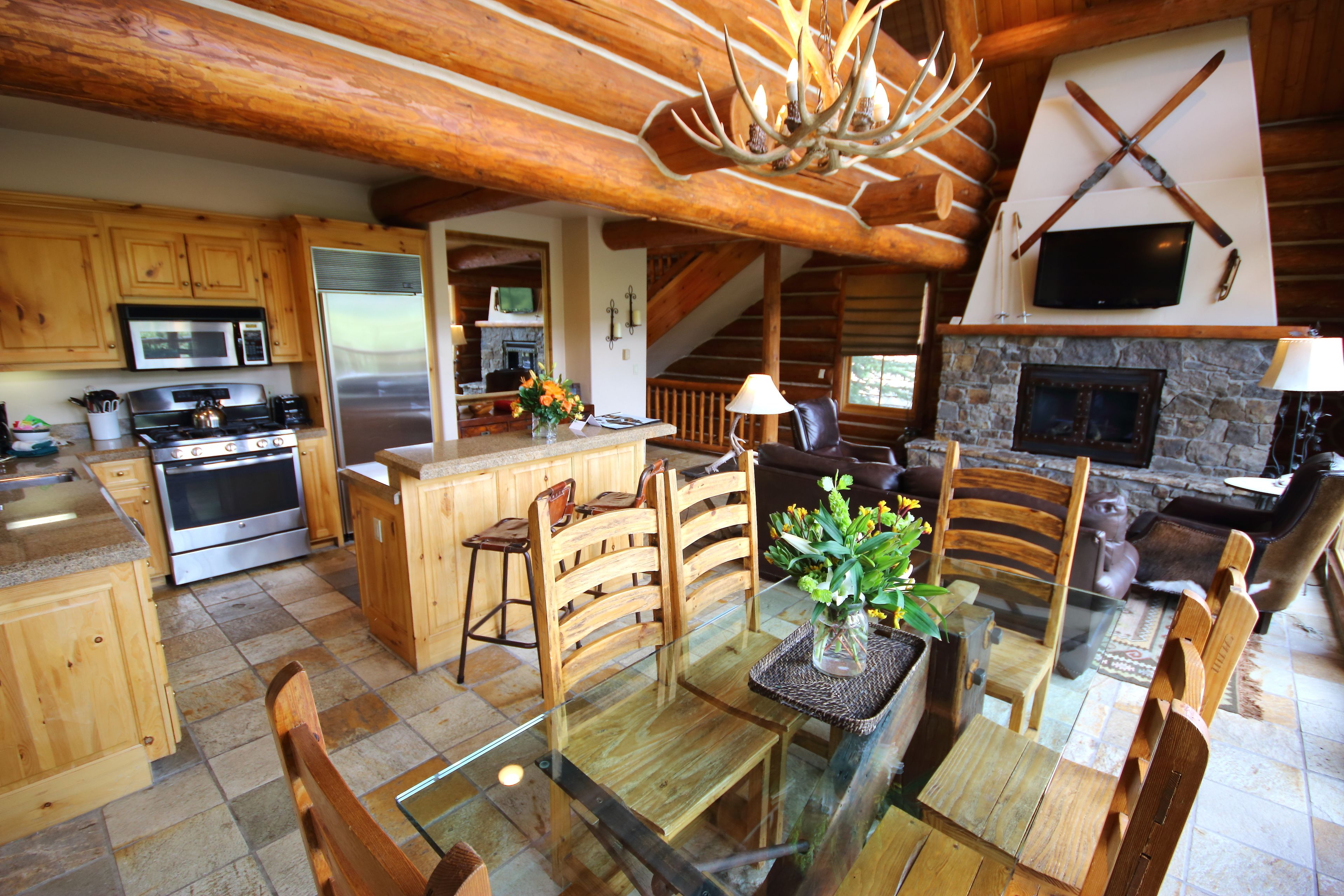 A rustic cabin interior with a kitchen, dining area, and living room.