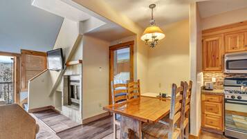 A dining area with a wooden table and chairs, a built-in oven, and a view of the outdoors.
