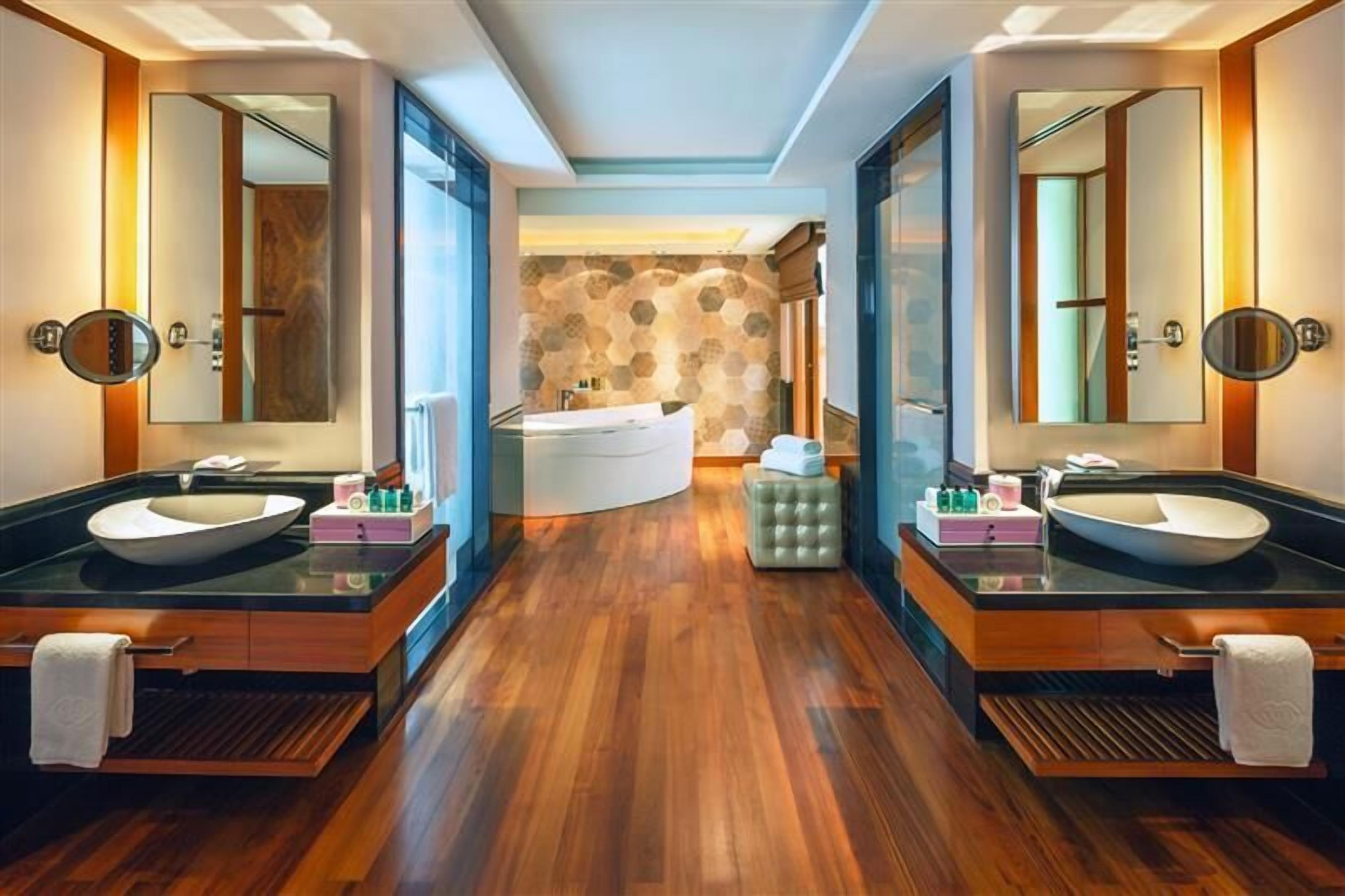 Une salle de bain moderne avec deux lavabos, un grand miroir et une baignoire.