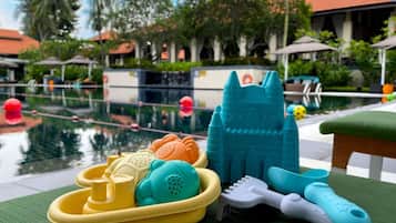Relax by the pool surrounded by palm trees and a castle-shaped water feature.