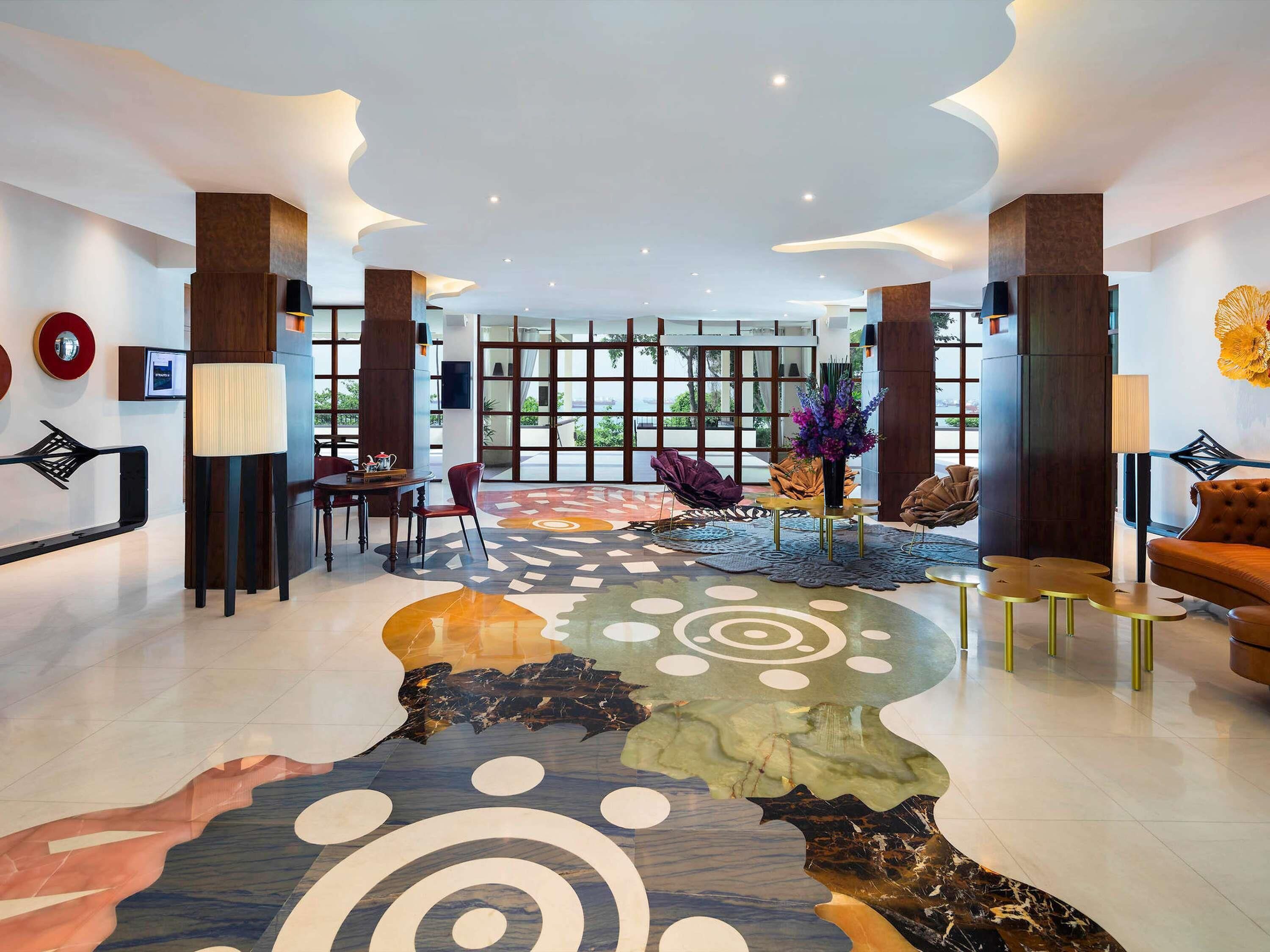 Eine moderne Lobby mit einer zentralen Sitzgruppe, einem gemusterten Boden und großen Fenstern.