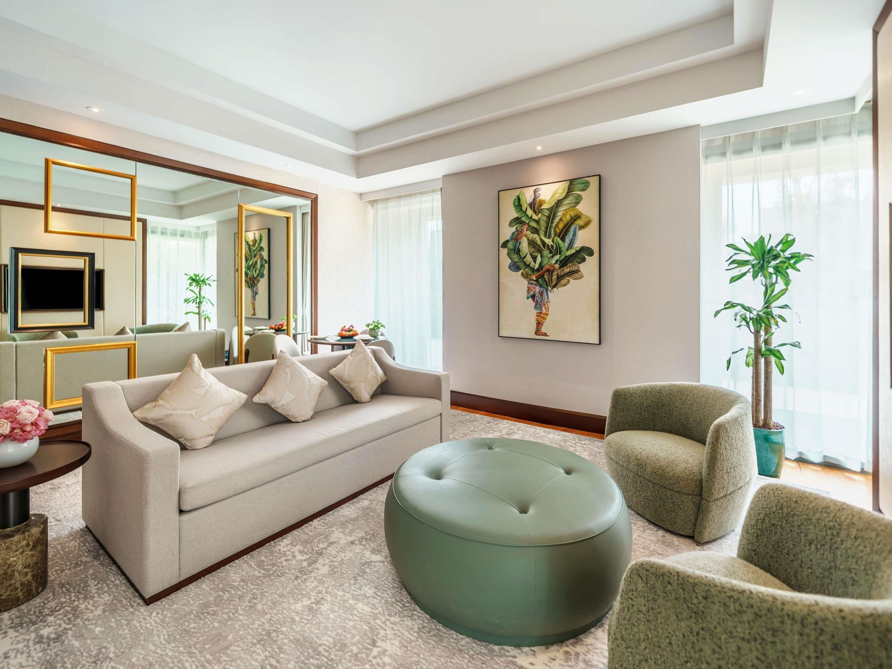 Ein modernes Wohnzimmer mit Sofa, Ottoman, Ohrensessel und einem großen Spiegel.