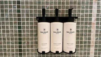 Three Balmain Paris products: shampoo, conditioner, and body wash, each in a black dispenser.
