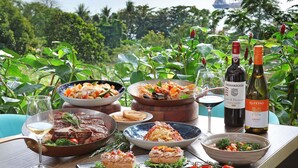 A table set with various dishes, wine bottles, and a scenic view. - Sofitel Singapore Sentosa (Singapore)