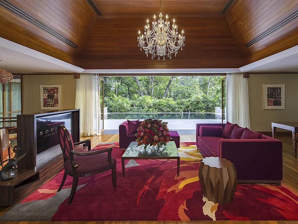 A spacious living room with a large window, a chandelier, and a television.