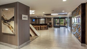 A modern hotel lobby with a bar area, a large abstract painting, and a sign for the Marriott Bonvoy hotel.