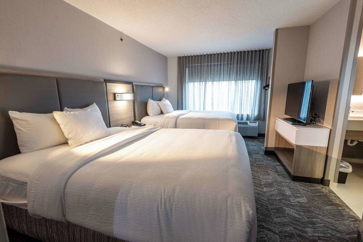 Een hotelkamer met twee bedden, een televisie en een bureau.