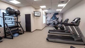 A fitness room with treadmills, a weight bench, and exercise balls.
