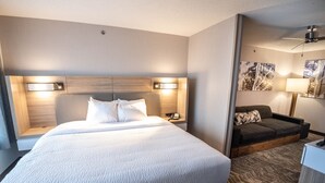 A hotel room with a large bed, bedside lamps, a sofa, and artwork on the walls.