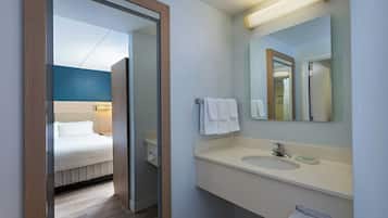 Un baño de hotel con lavamanos, espejo y toallero.
