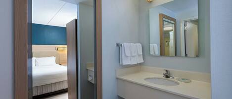 Un baño de hotel con lavamanos, espejo y toallero.