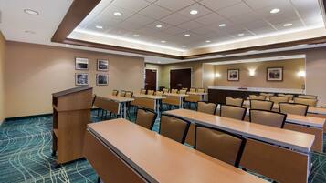 A conference room with multiple tables and chairs, a podium, and framed pictures on the walls.