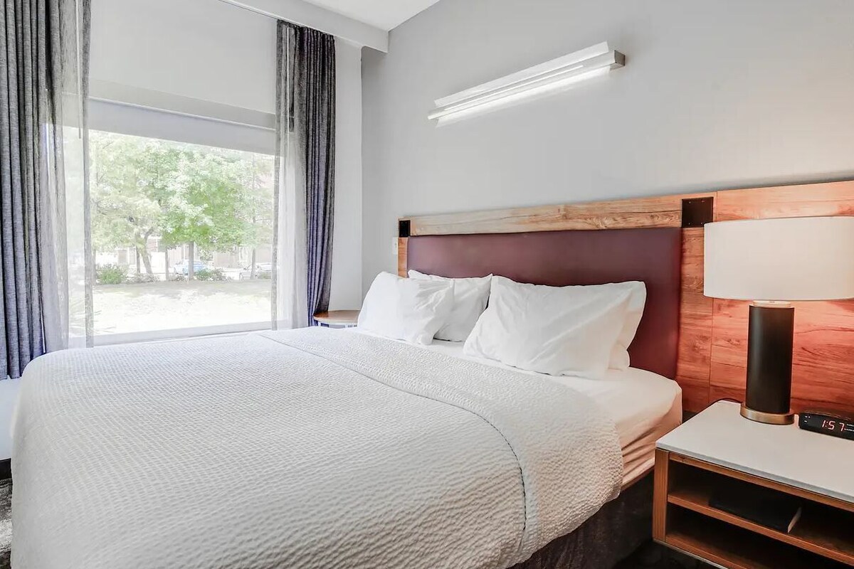 Escritorio, cortinas opacas, tabla de planchar con plancha