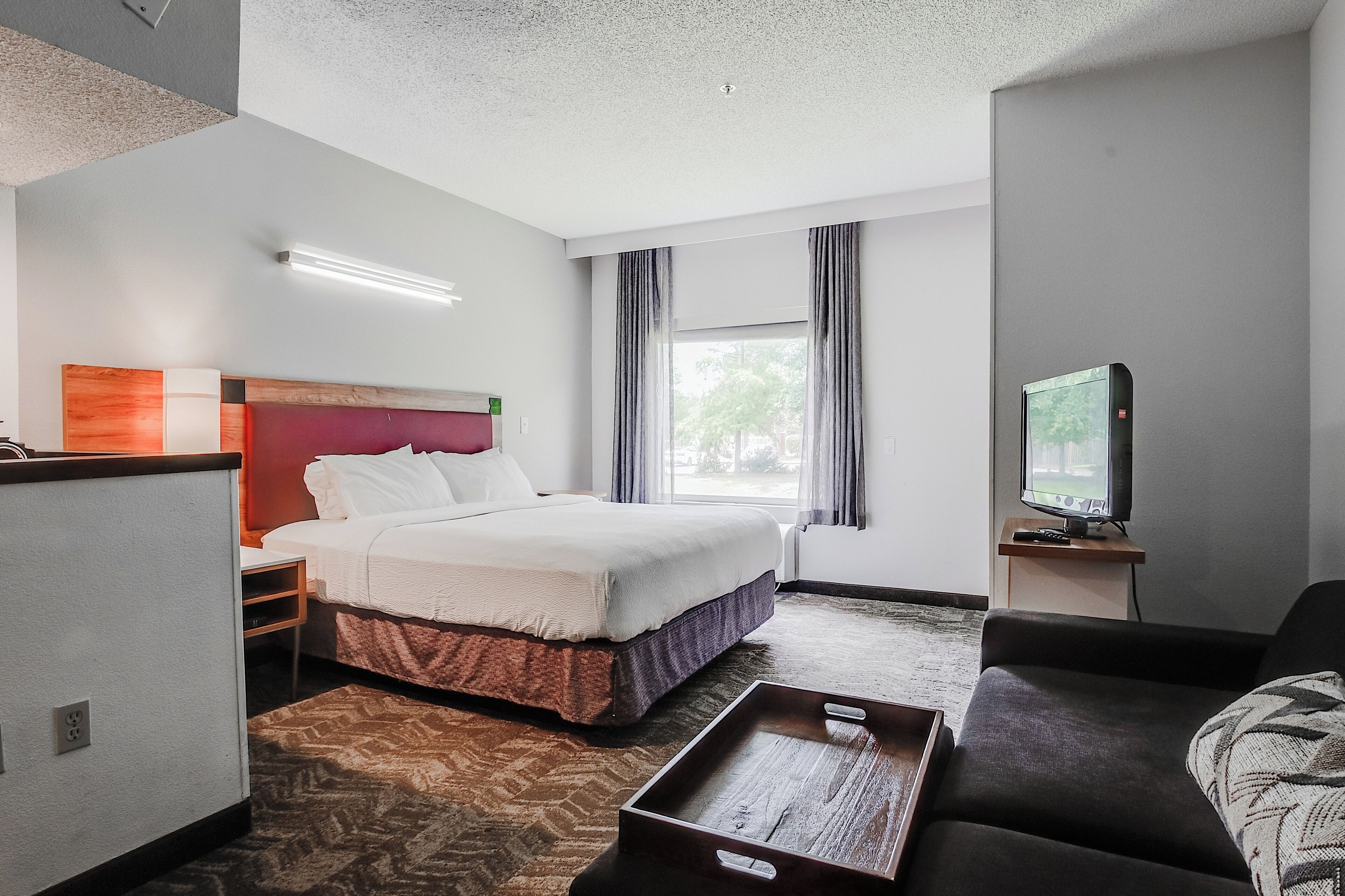 Ein Hotelzimmer mit Bett, Fernseher, Sofa und Schreibtisch.
