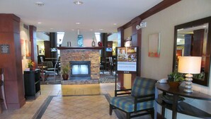 A lobby with a stone fireplace, a television, and a reception desk with a lamp. - Sonesta ES Suites San Antonio Northwest - Medical Center (San Antonio)