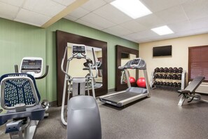 A gym with cardio machines, weightlifting equipment, and a mirror.