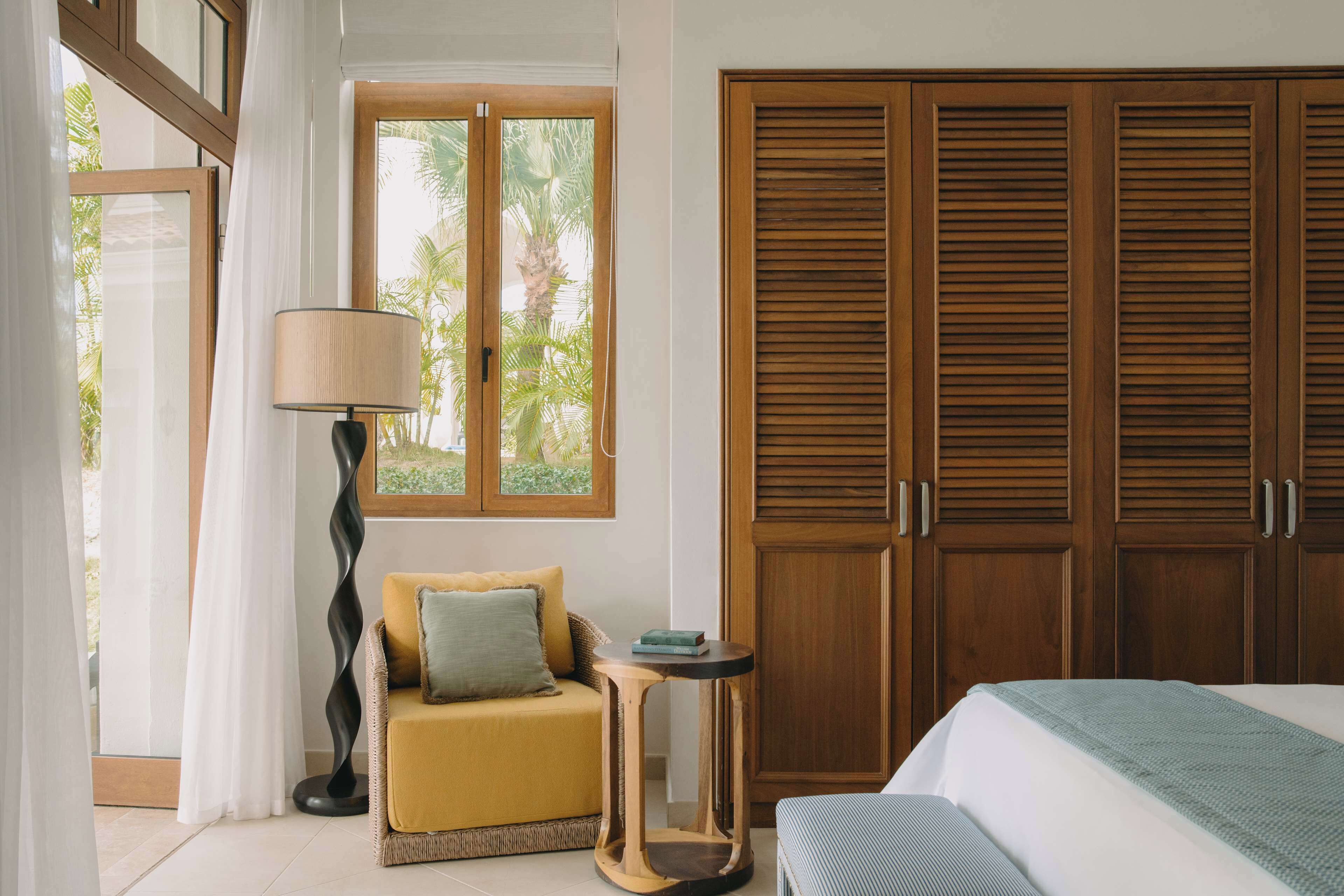 A bedroom with a bed, a sofa, a lamp, a wardrobe, and a window with curtains.