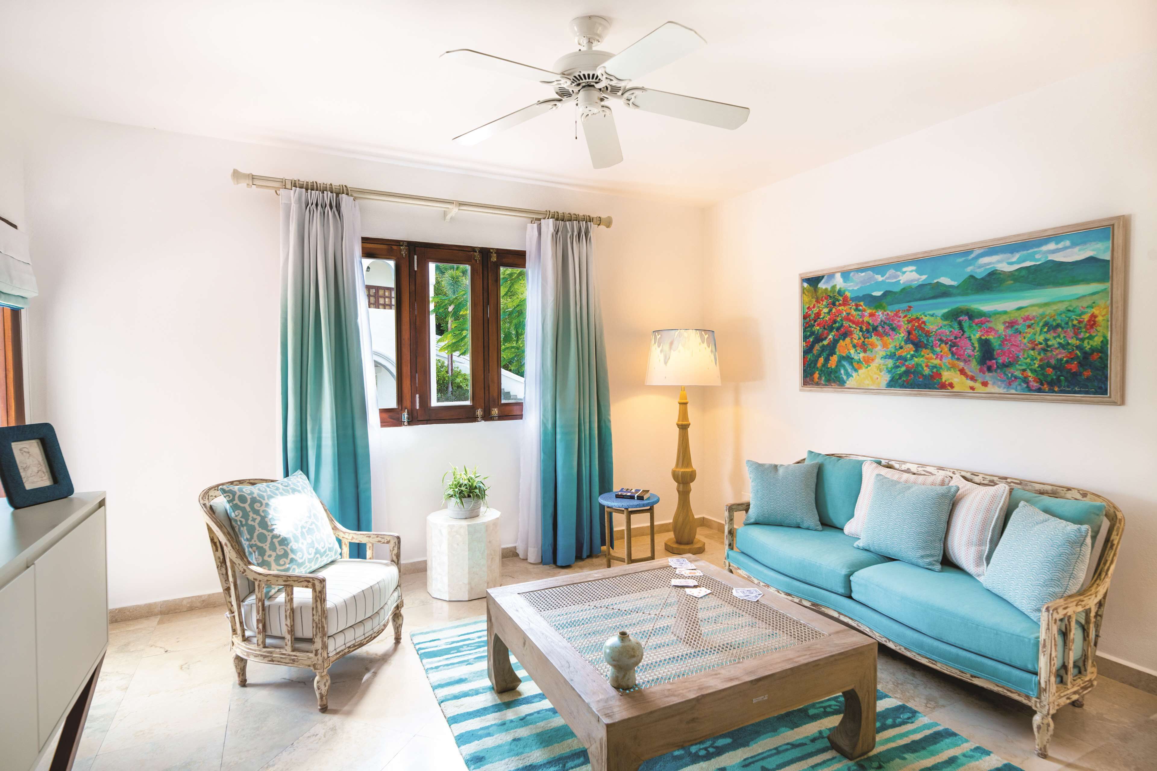 A living room with a sofa, armchair, coffee table, and a painting on the wall.