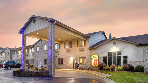 Un motel con entrada cubierta, un letrero de 'Super 8' y un estacionamiento.