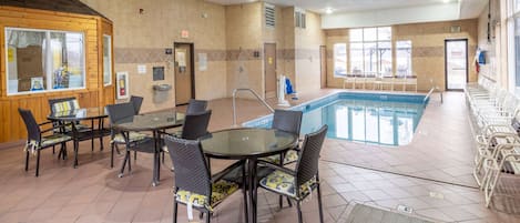 A hotel lobby with a pool, seating area, and a reception desk.