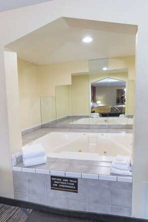 A bathroom with a large bathtub, a glass shower enclosure, and a sign instructing to read instructions on the credenza. - Super 8 by Wyndham Big Rapids (Big Rapids)
